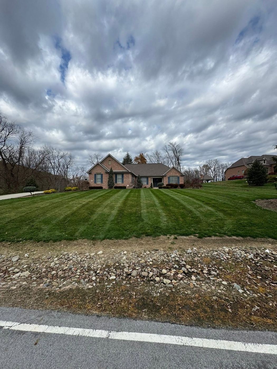 Freshly mowed striped lawn in front of a brick home on an overcast day