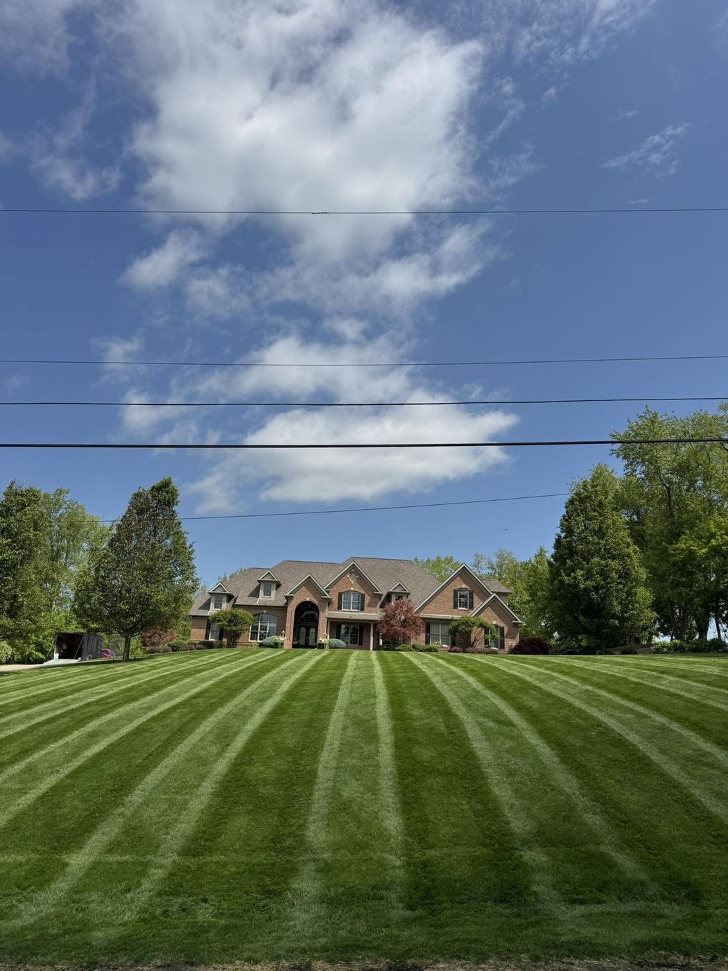 Sweeping striped lawn in front of a large brick estate home
