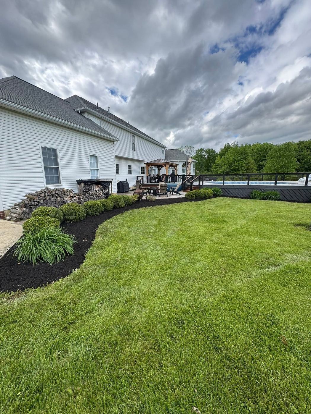 Crisp curved bed edging with fresh mulch bordering a backyard lawn and pool deck