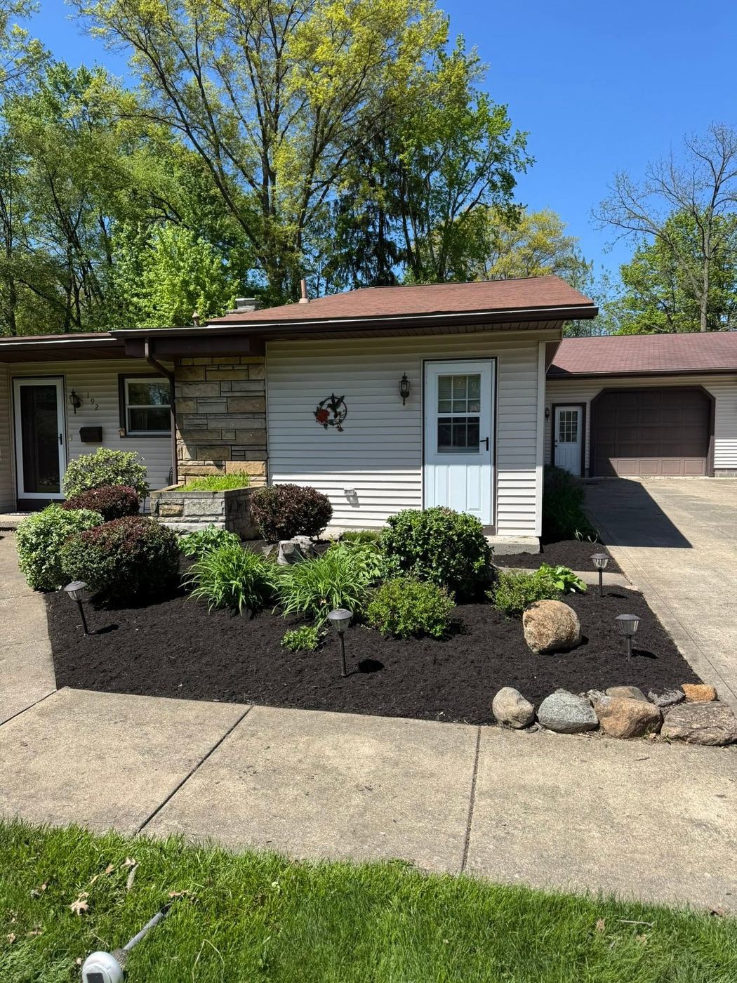 The same ranch home front bed after Campbell's reshaped the shrubs, set boulders and laid fresh dark mulch