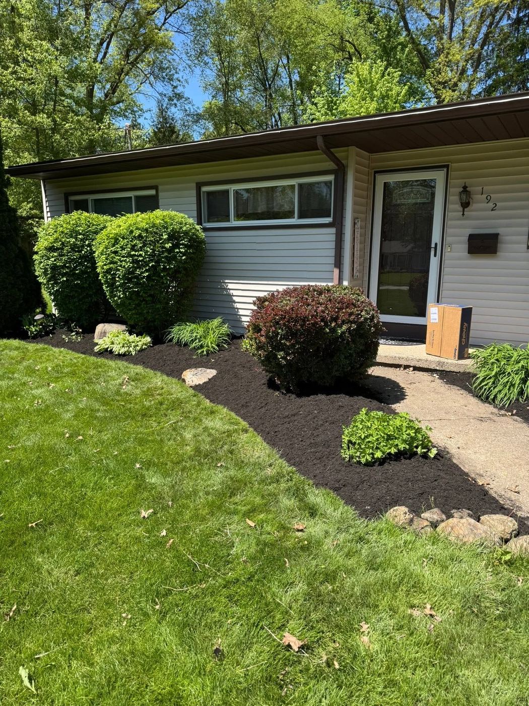 Neatly shaped shrubs set in fresh mulch along a ranch home's entryway